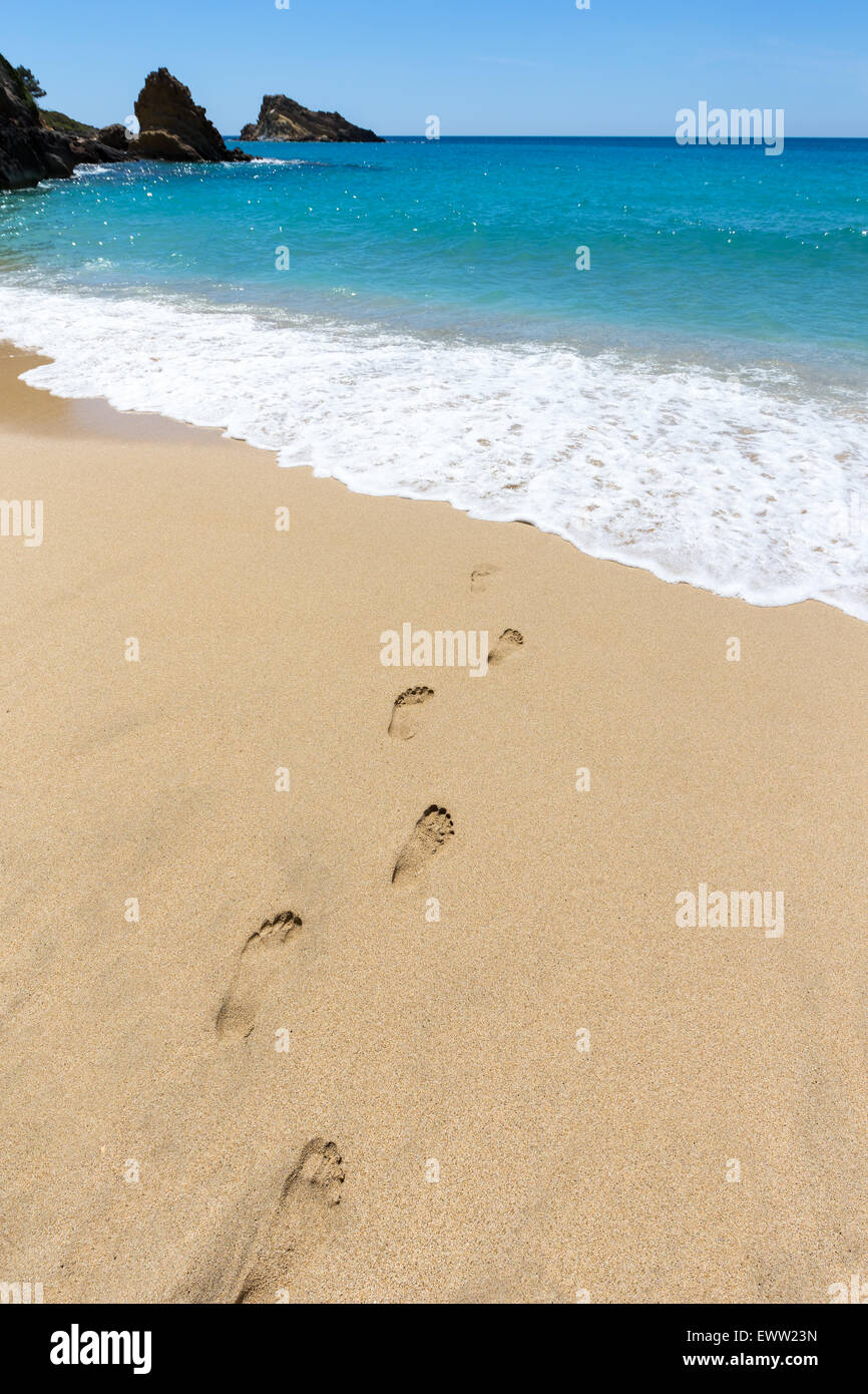 Footsteps in sandy beach leading to blue sea at coast on island in Greece Stock Photo