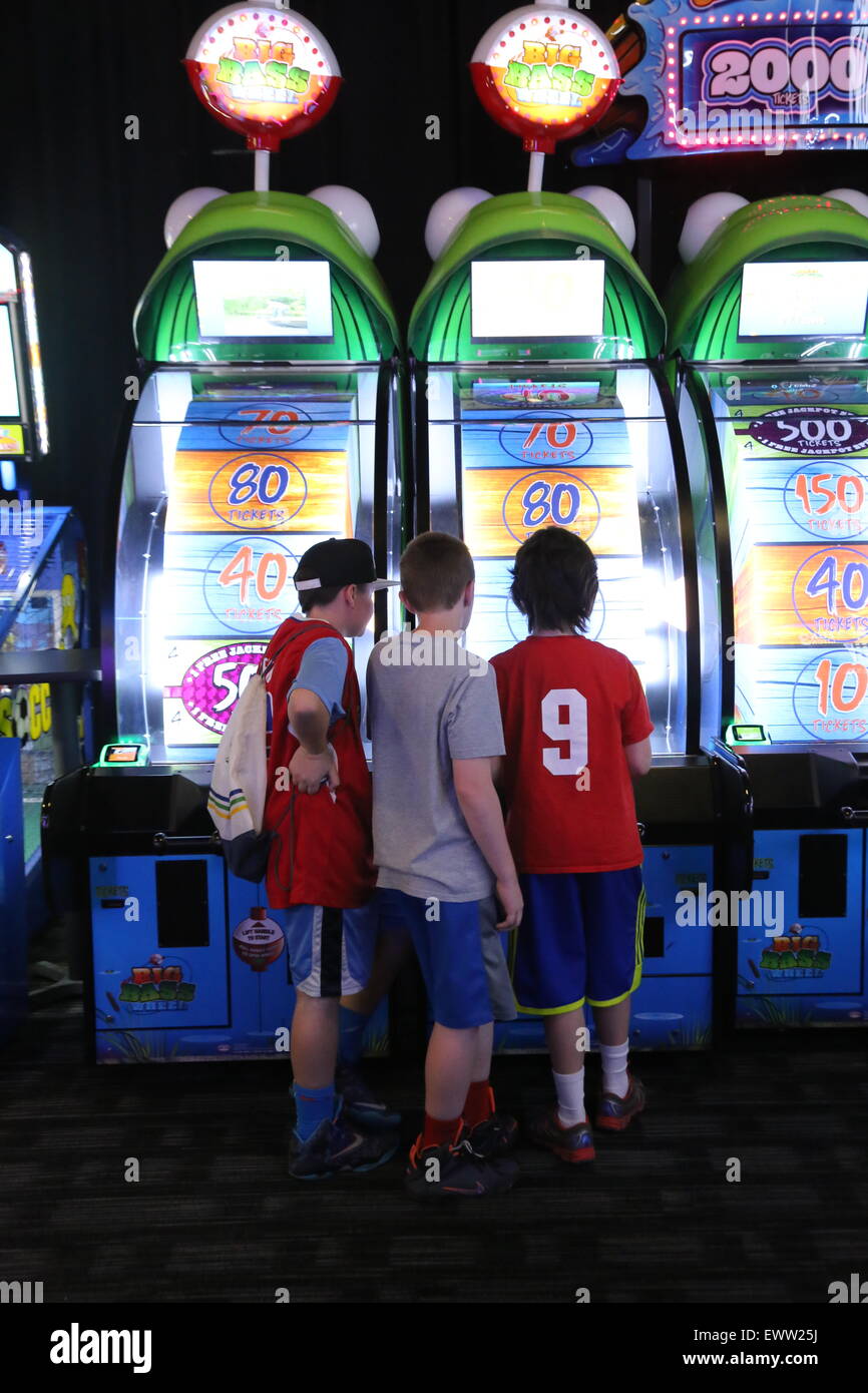 Three boys playing a game at an arcade Stock Photo
