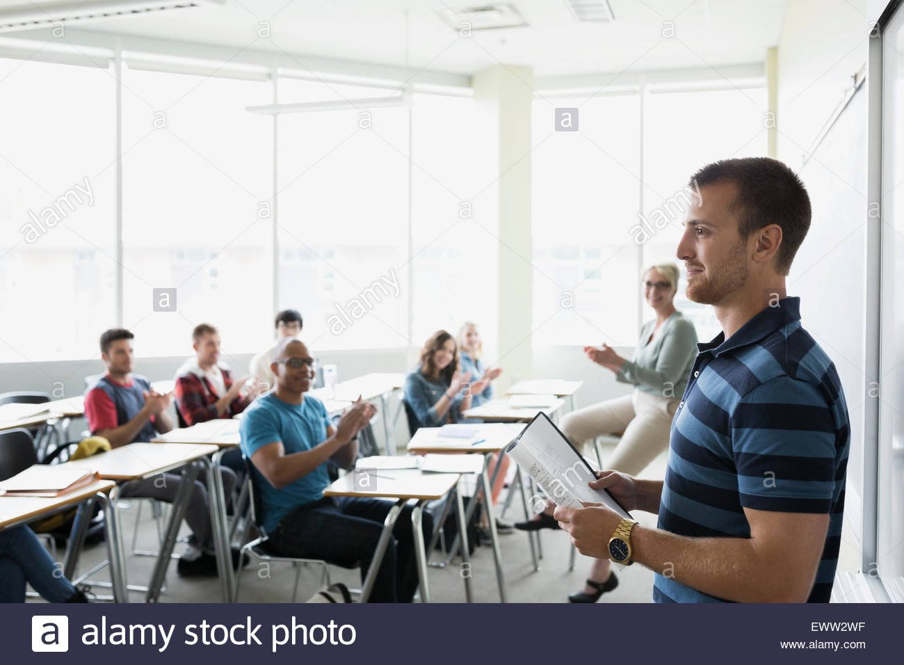 Professor and classmates clapping college student giving presentation Stock Photo