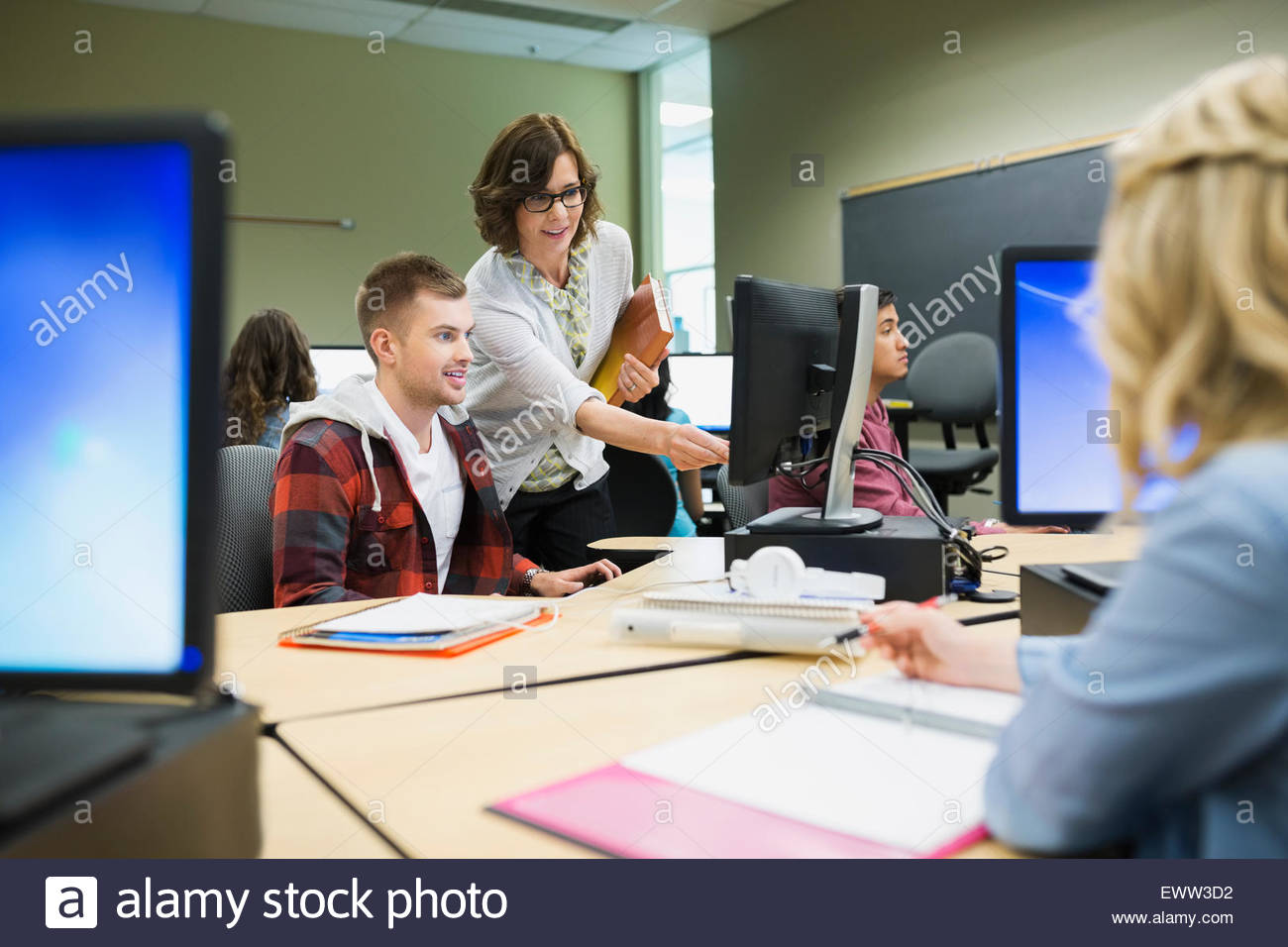 Professor helping college student at computer in classroom Stock Photo