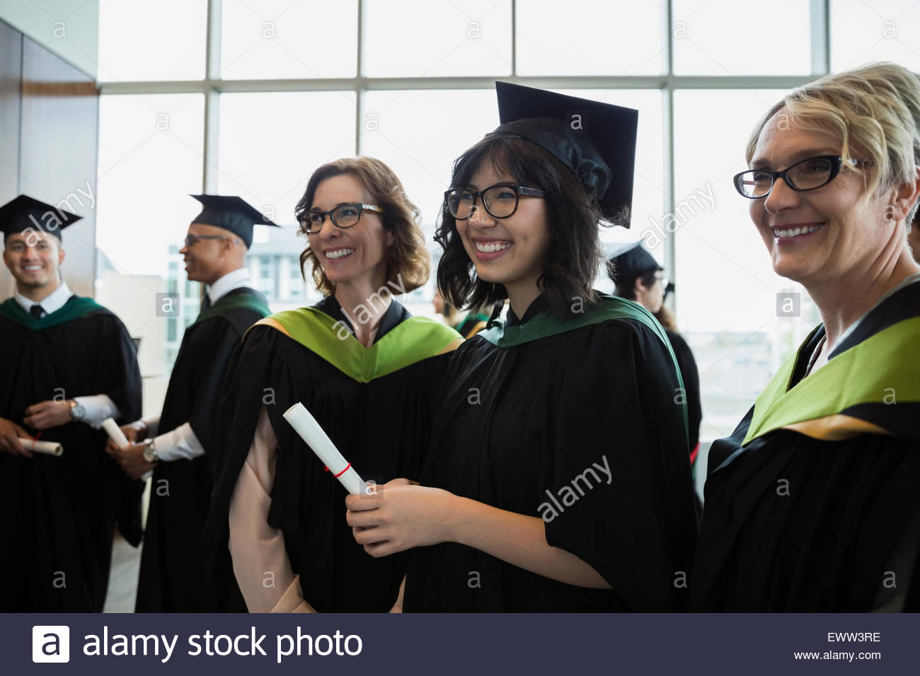 Smiling college graduate and professors cap and gown Stock Photo