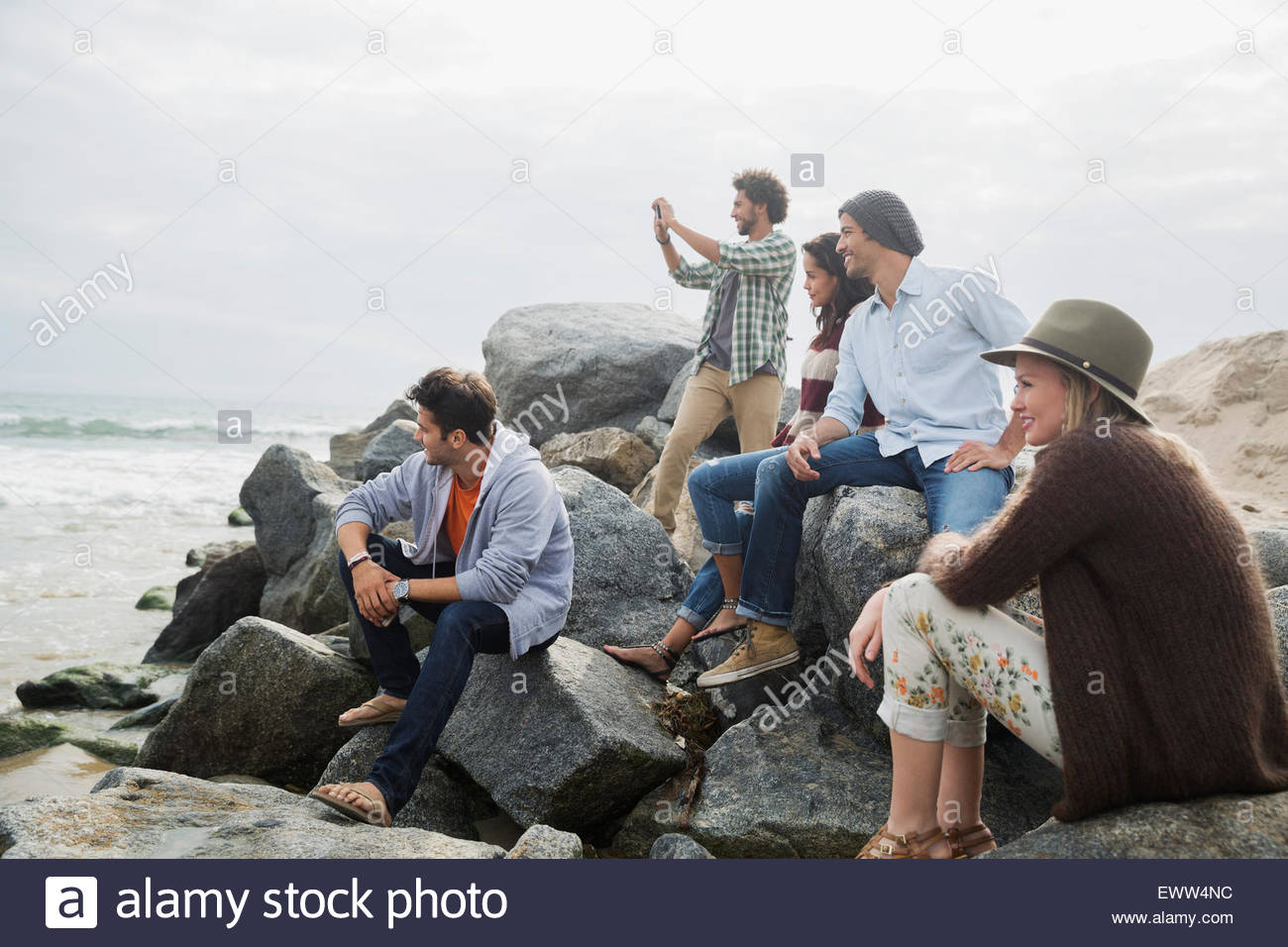 Friends hanging out on beach rocks Stock Photo