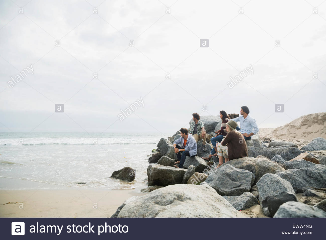 Friends looking at ocean view from beach rocks Stock Photo