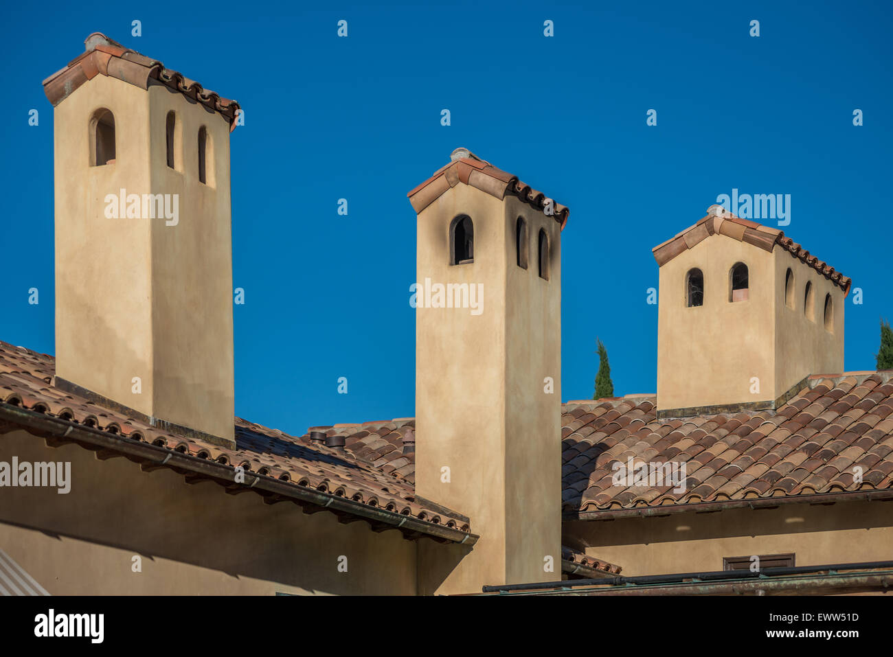 3 concrete towers jutting from clay tile rooftops Stock Photo