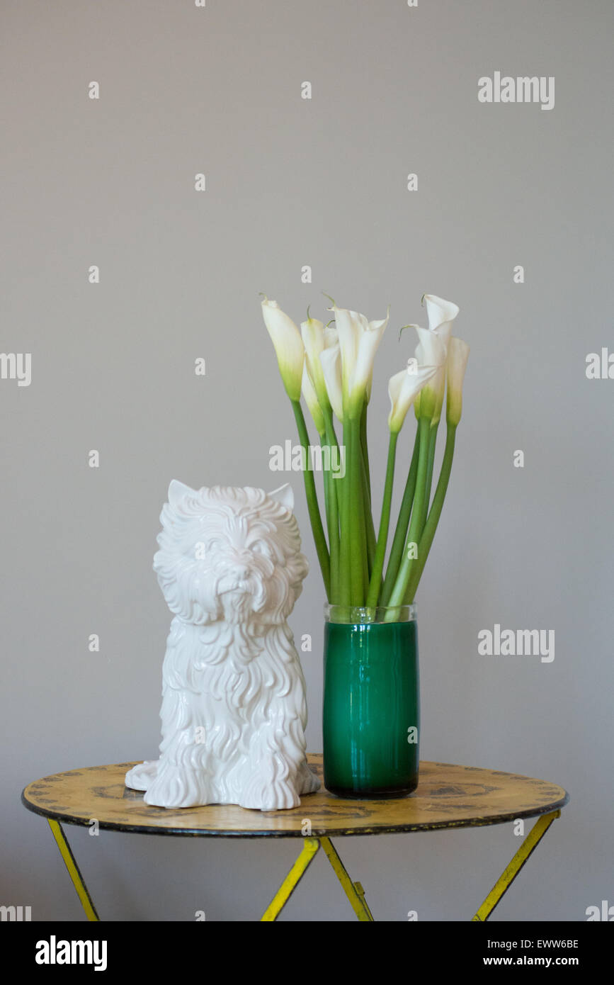 White ceramic 'Puppy Vase' by Jeff Koons next to Calla Lilies in a green glass vase Stock Photo
