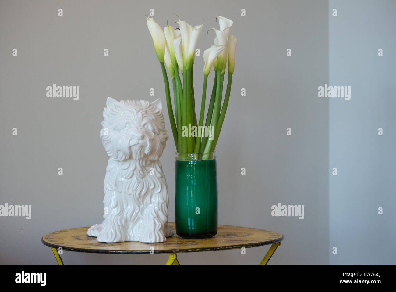 White ceramic 'Puppy Vase' by Jeff Koons next to Calla Lilies in a green glass vase Stock Photo