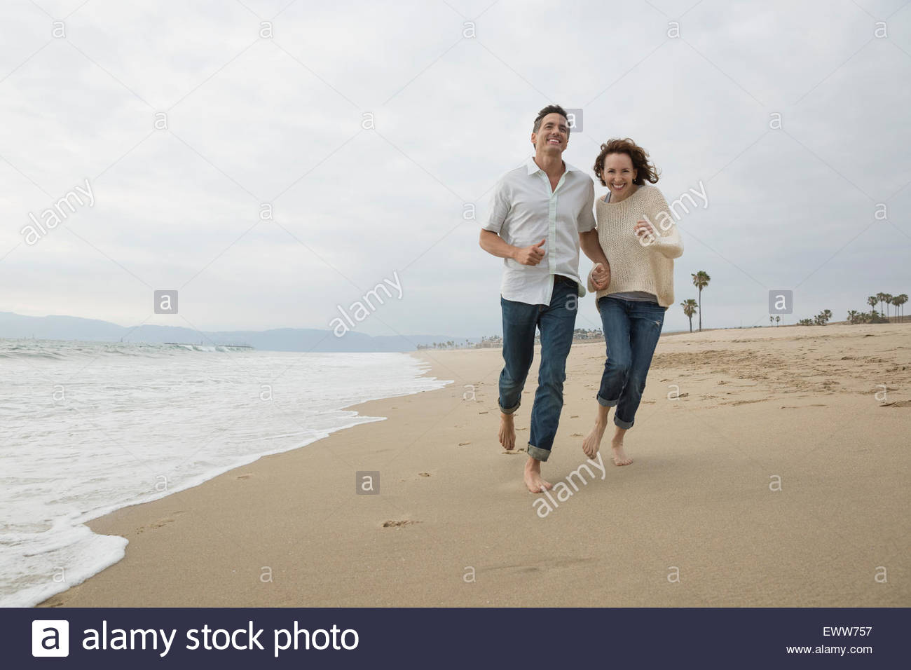 Energetic couple running on beach Stock Photo