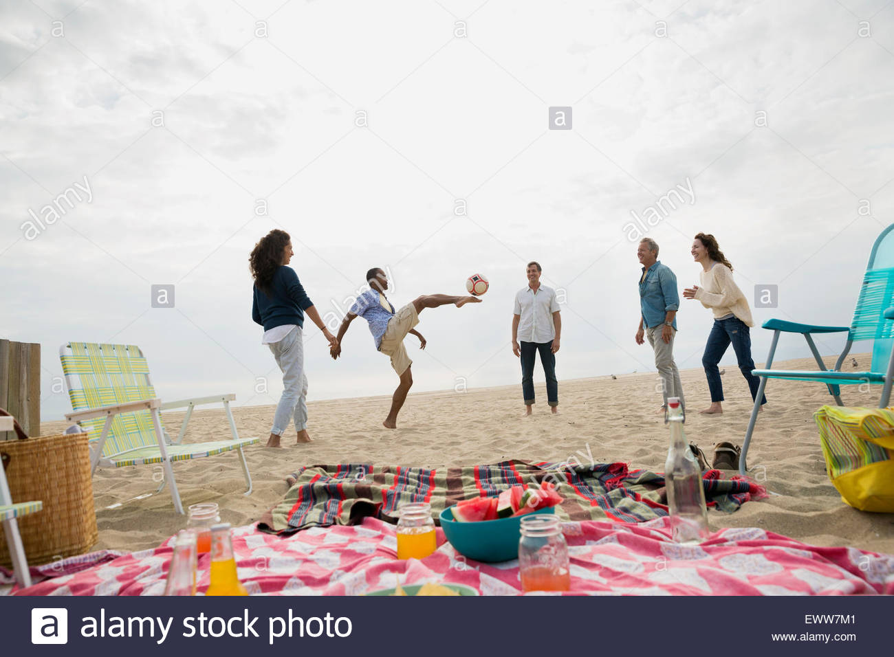 Friends playing soccer near beach picnic Stock Photo
