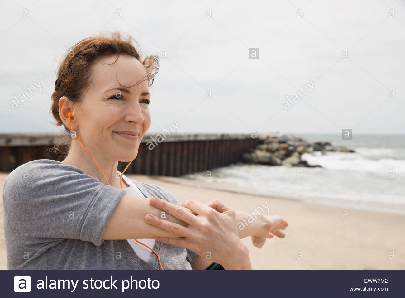 Smiling woman stretching arm on beach Stock Photo