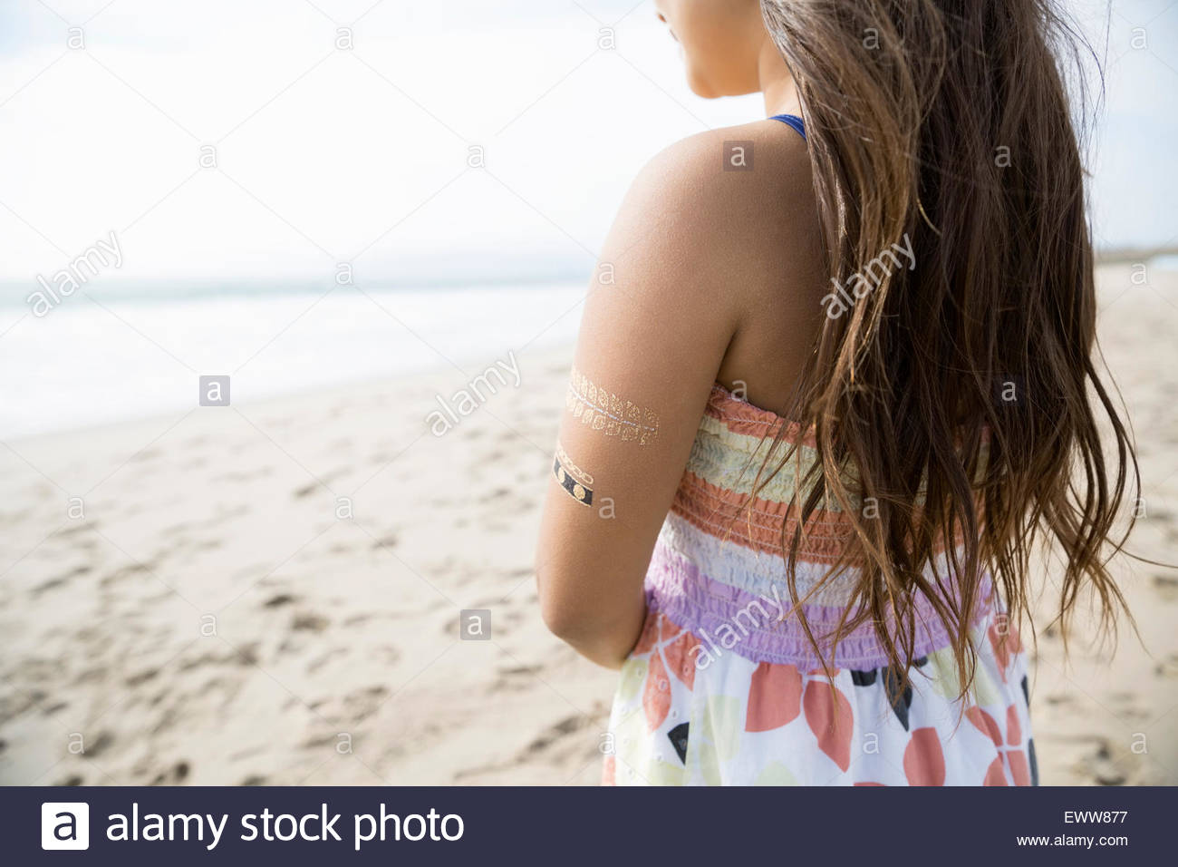 Pensive girl with henna tattoos on arm beach Stock Photo