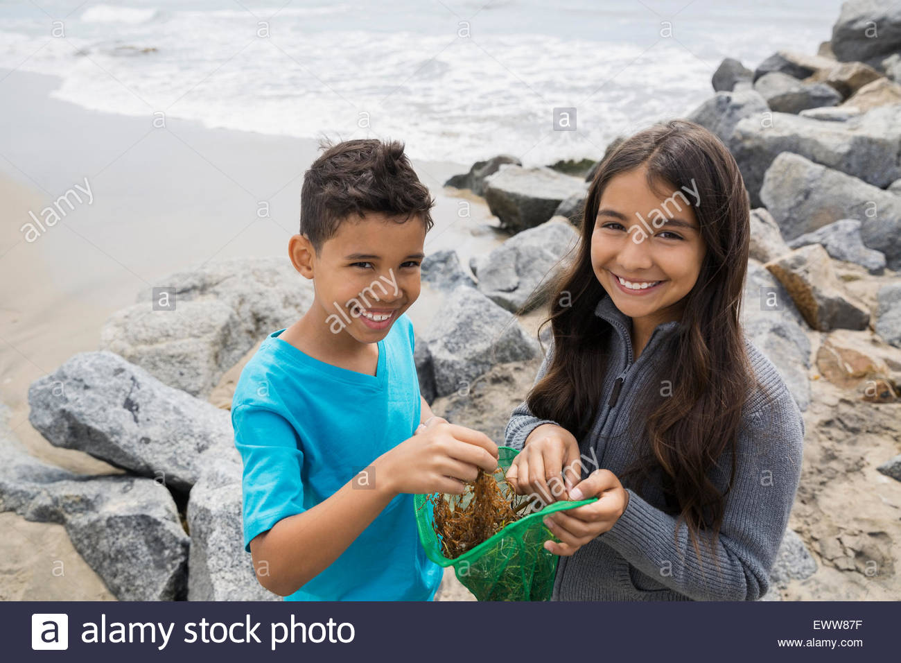 Portrait smiling brother and sister fishing net beach Stock Photo