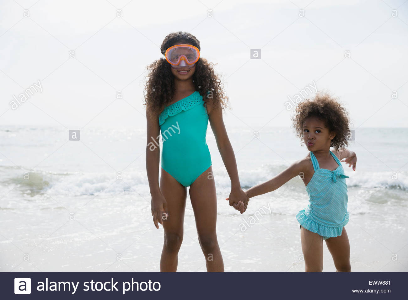 Portrait sisters in bathing suits wading in ocean Stock Photo Alamy