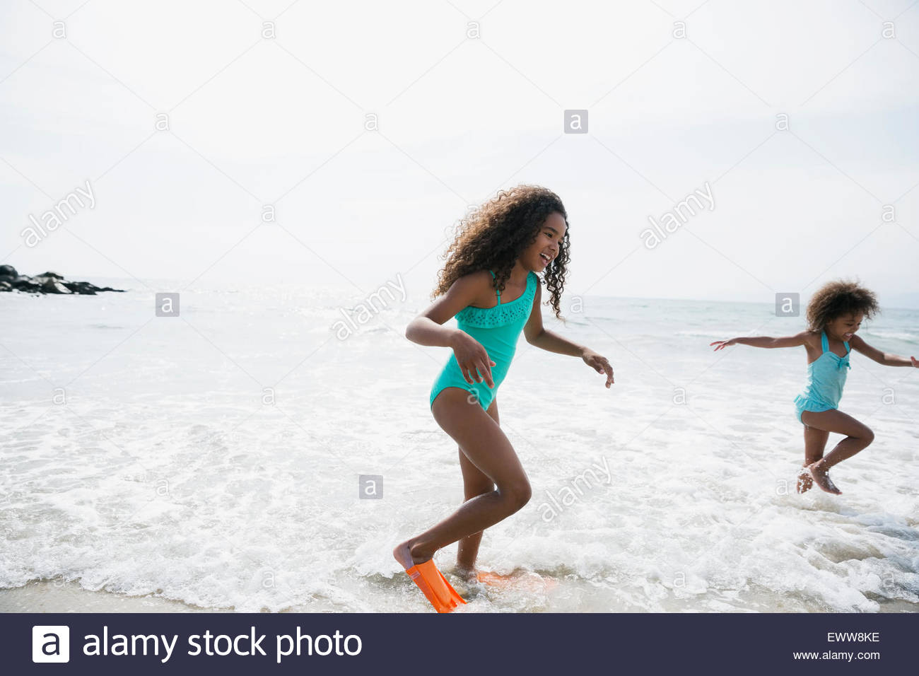 Sisters in bathing suits splashing in ocean Stock Photo