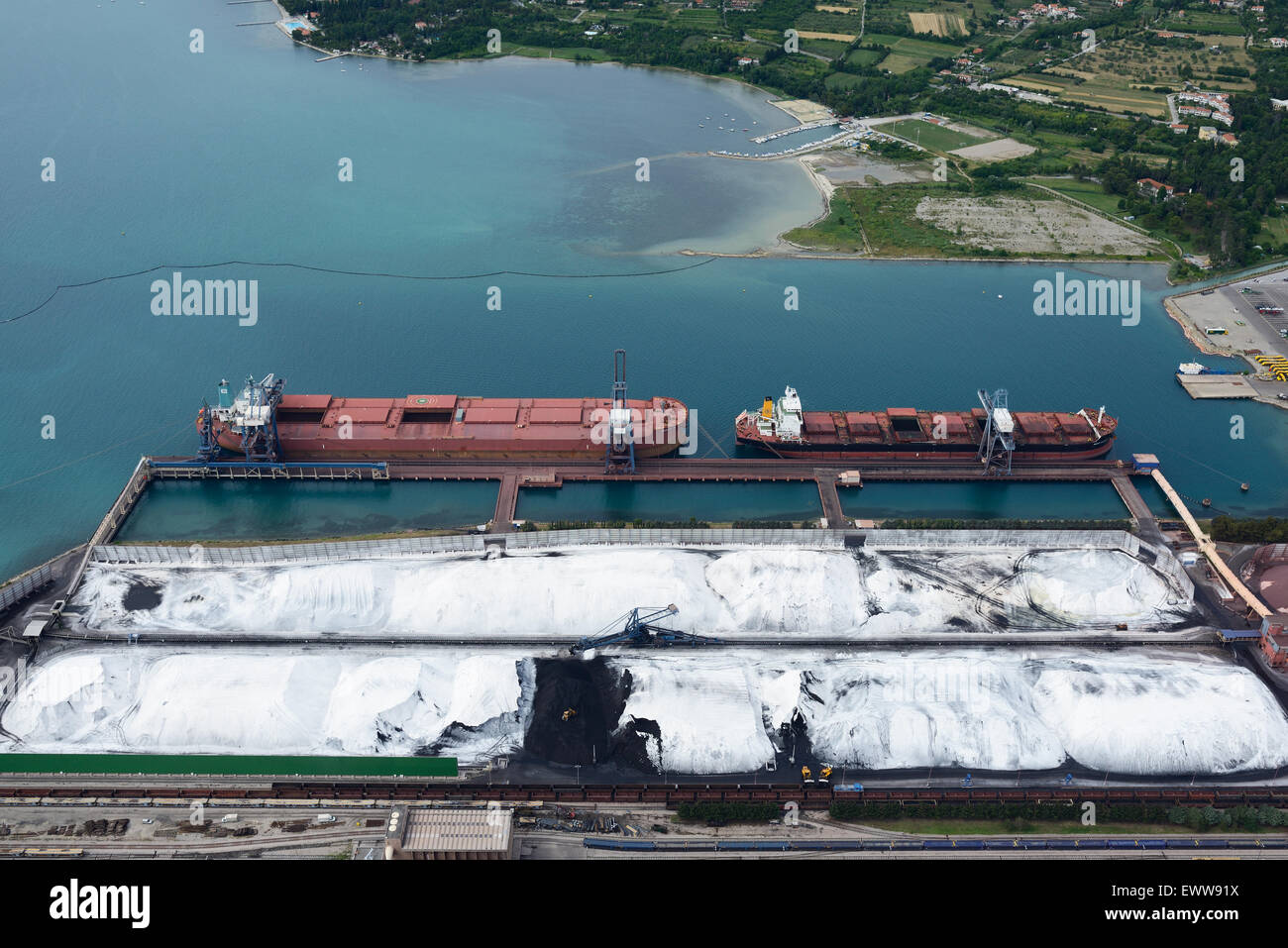AERIAL VIEW. Coal and iron ore storage (under the white cellulose to prevent airborne pollutants). Ankaran (aka Ancarano, its Italian name). Slovenia. Stock Photo