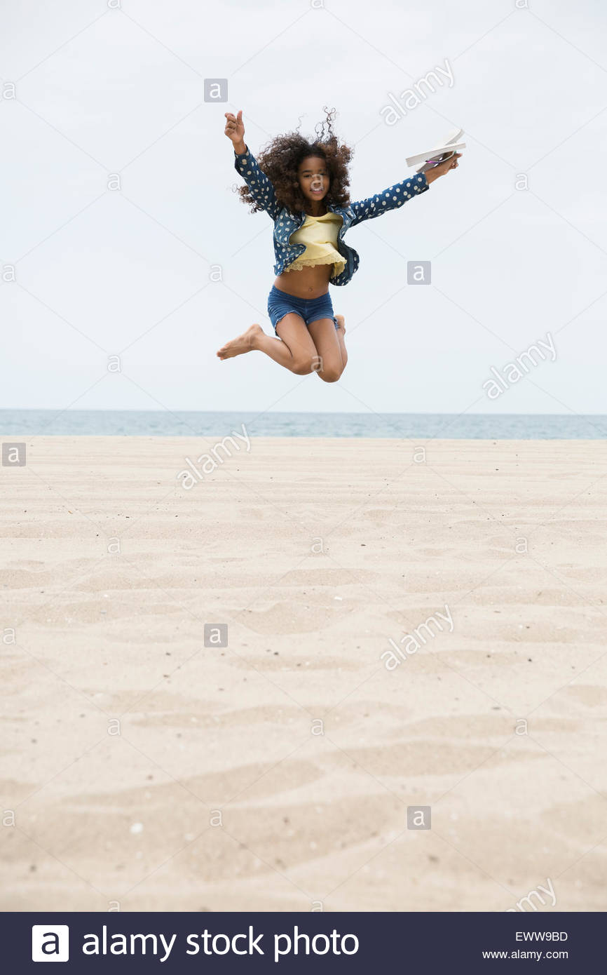 Portrait exuberant girl jumping on beach Stock Photo