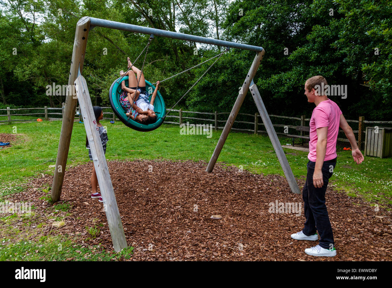 A Family Playing On The Swings, Play Area, Sussex, UK Stock Photo