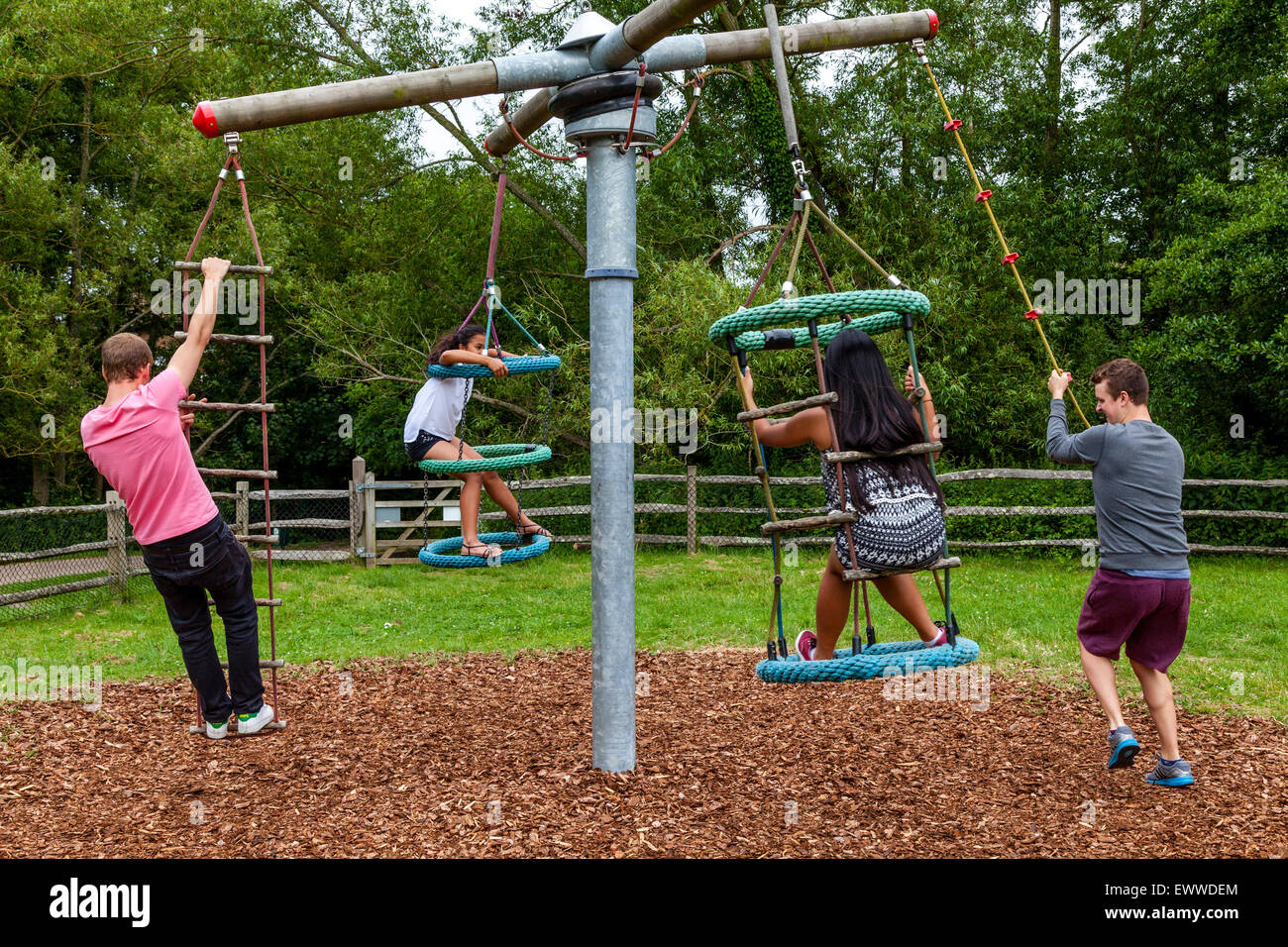 A Family Playing On The Swings, Play Area, Sussex, UK Stock Photo