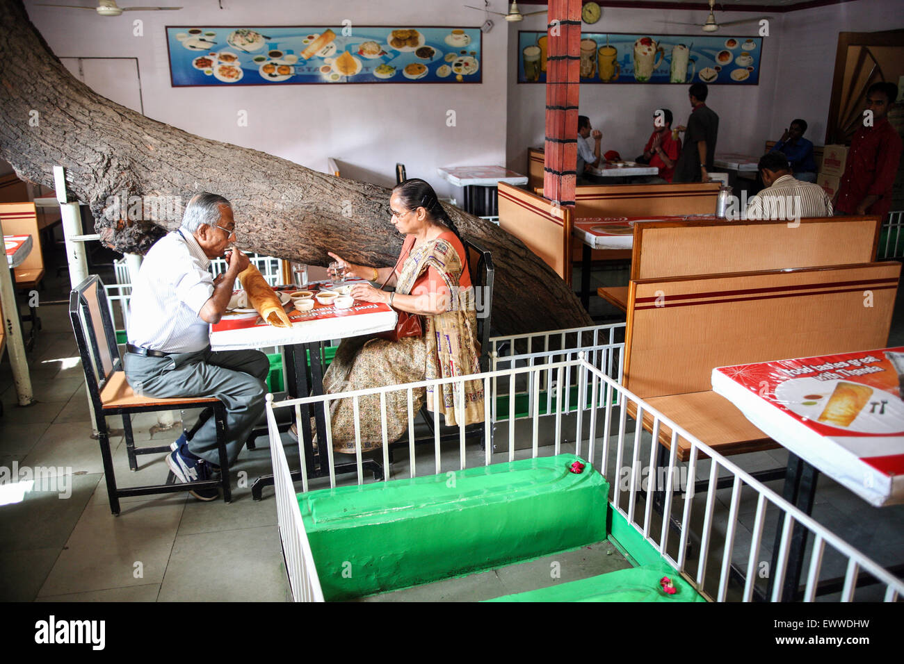 'Lucky Tea Stall' with its tables flanked by green painted Muslim graves and a tree trunk springs through the roof of the shop! Stock Photo