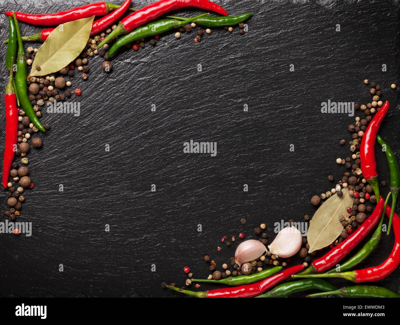 Chili pepper, peppercorn, garlic and bay leaves on black stone table with copy space Stock Photo