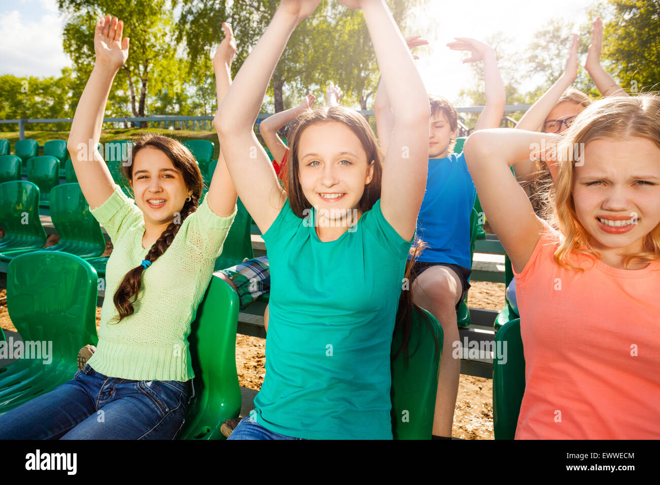 Happy teens hold arms up during game on tribune Stock Photo