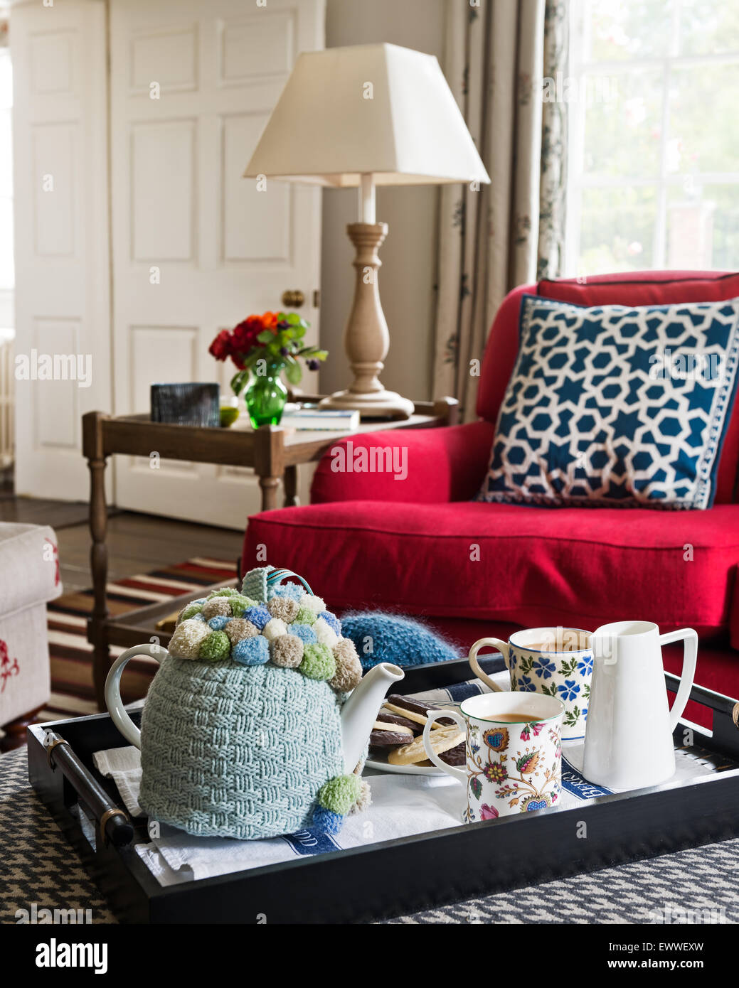 Tea is served on a black lacquer tray on an ottoman upholstered in Pienza Rafano fabric by Kathryn Ireland Stock Photo