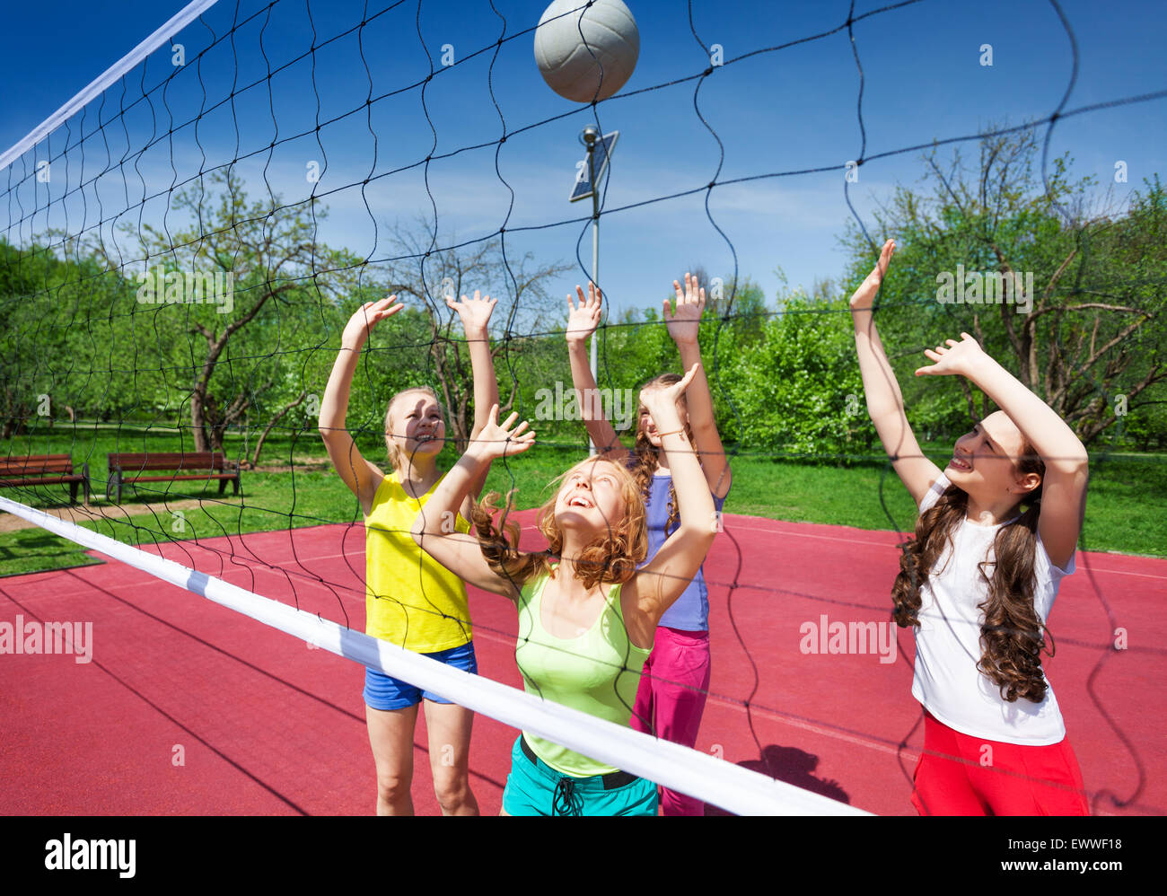 View through volleyball net of playing girls Stock Photo