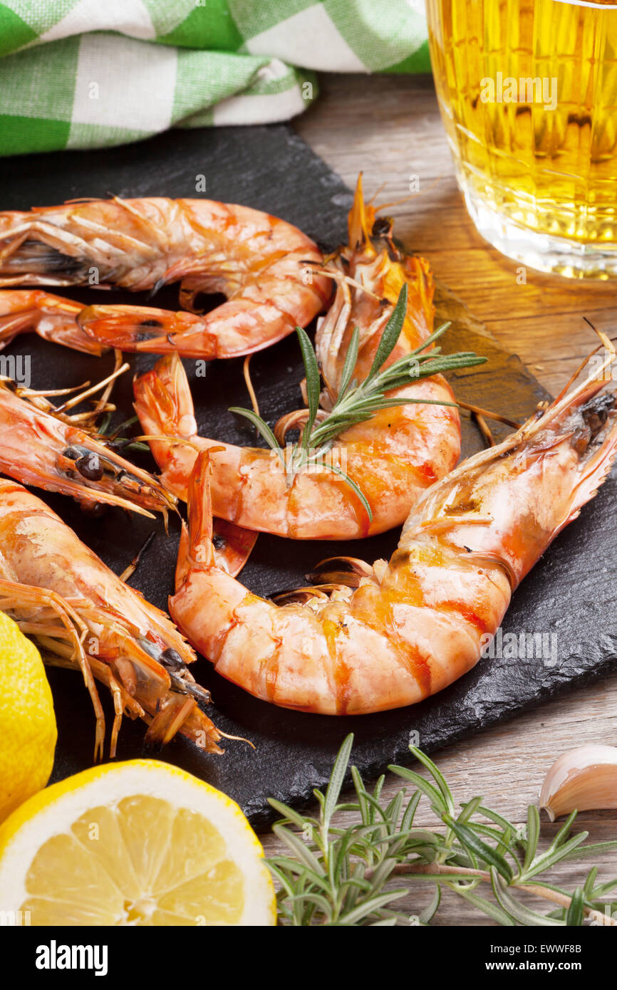 Grilled shrimps on stone plate and beer mug on wooden table Stock Photo