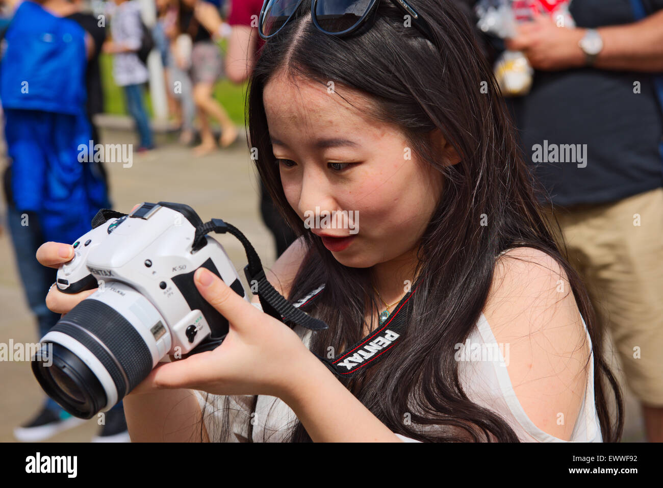 Pretty Asian woman examining screen on SLR digital camera Stock Photo