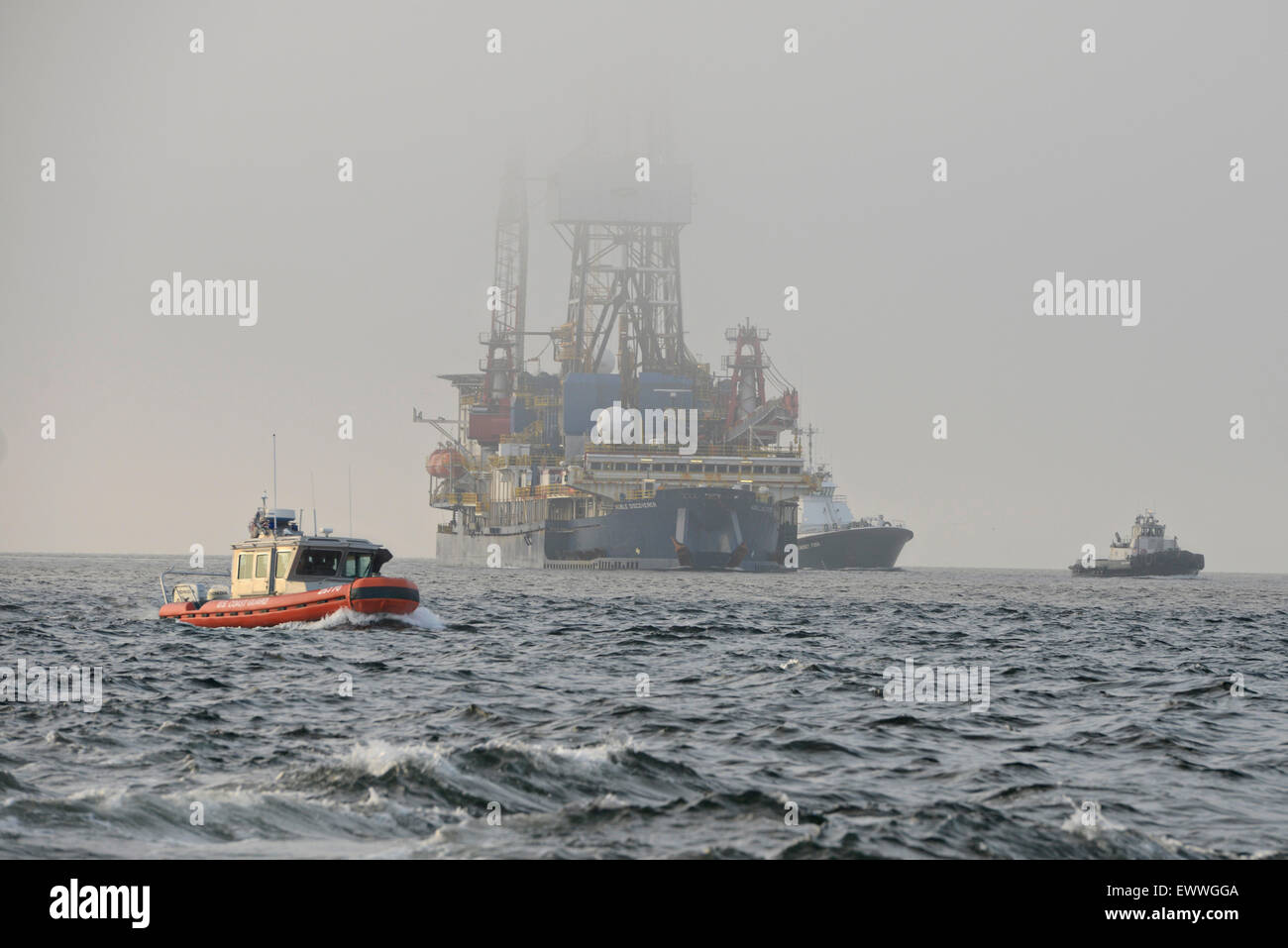 Coast Guard boats escort the deep arctic oil exploration ship Noble Discover as it transits the Puget Sound after departing June 30, 2015 from the Port of Everett, Washington. The Coast Guard enforced a 500-yard safety zone around the vessel as activists continued to try and block the ship. Stock Photo