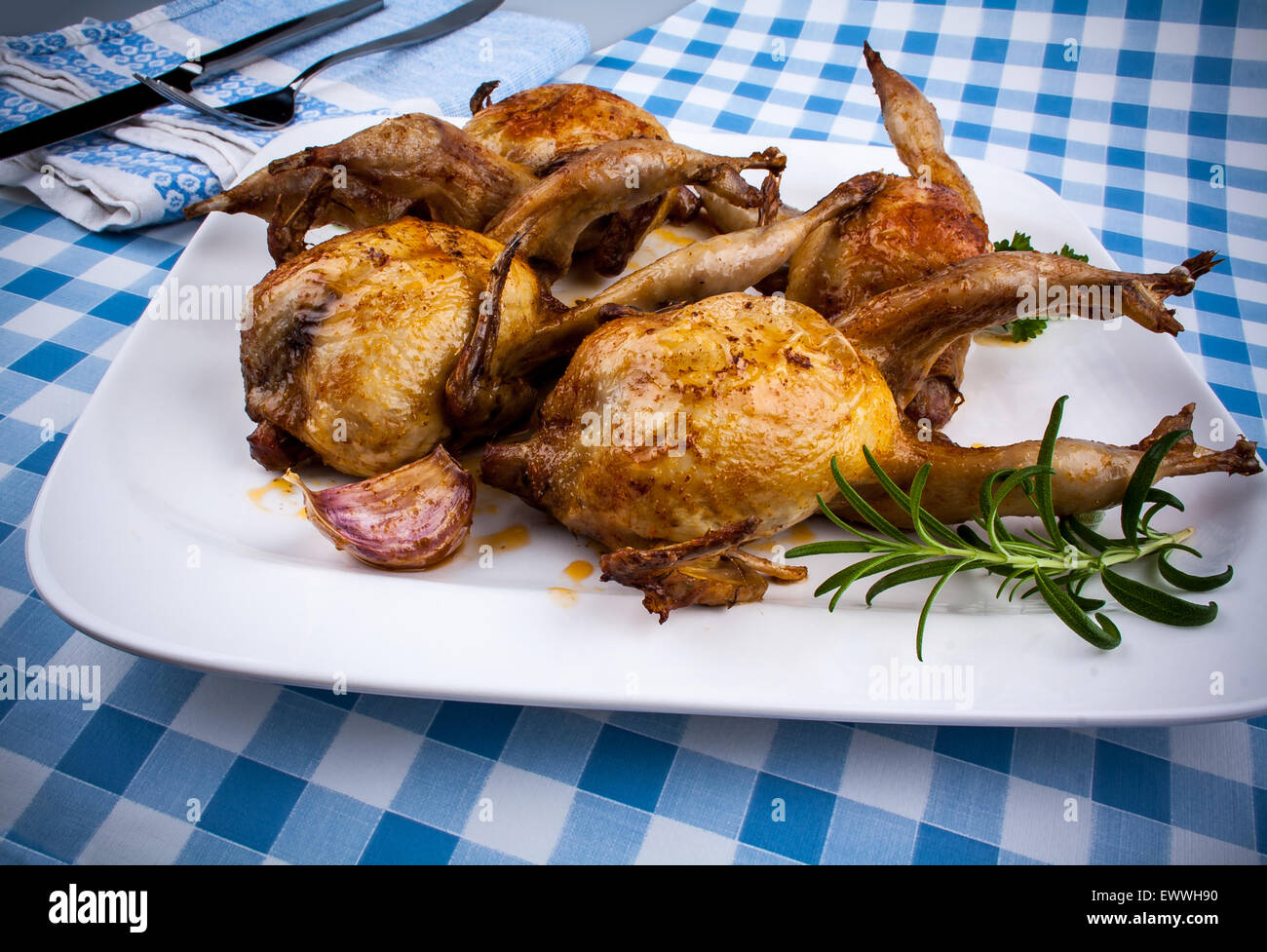 Four fried quail with gravy, garlic and rosemary, closeup Stock Photo
