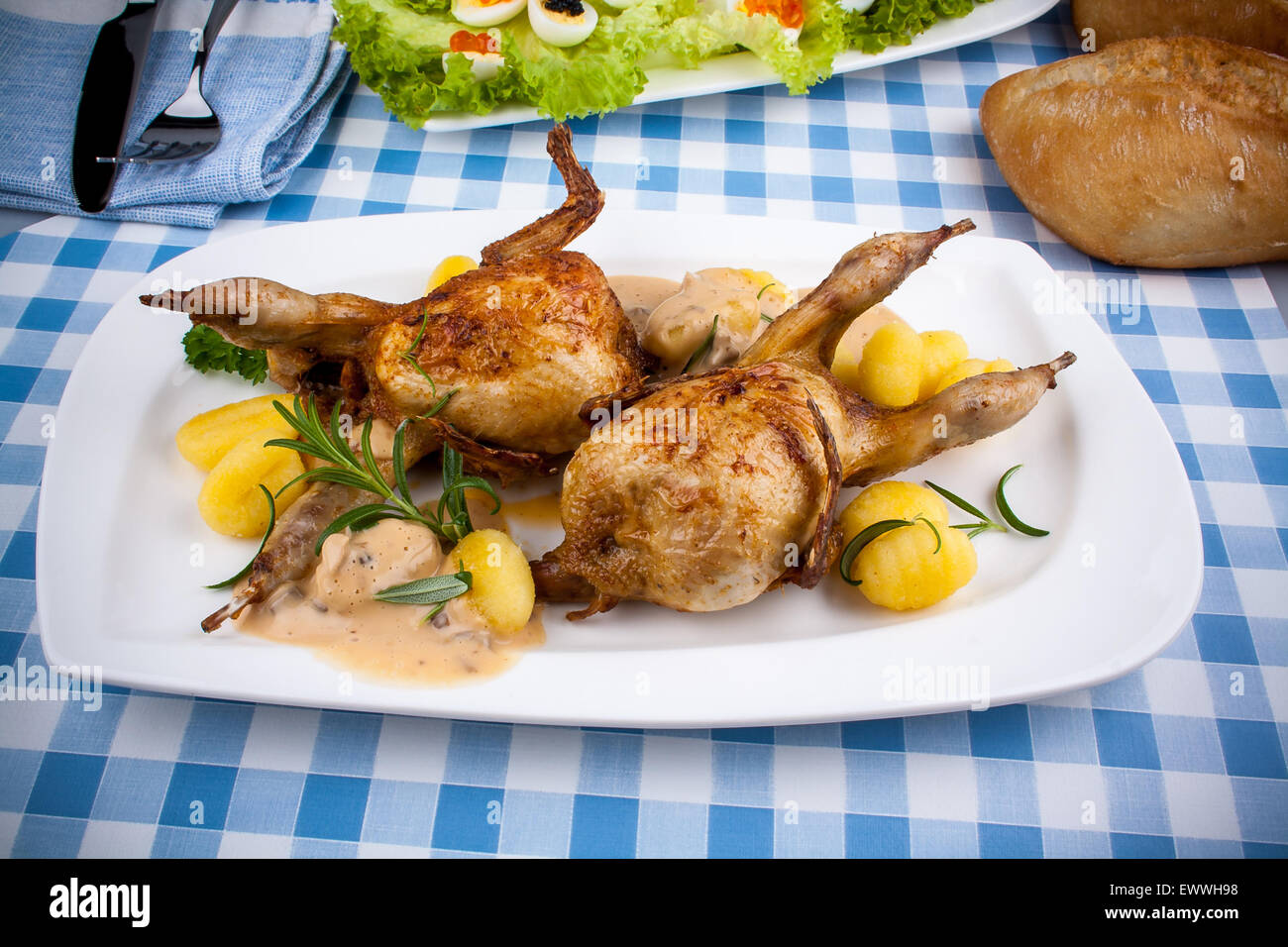 Two fried quail with gnocchi, gravy and rosemary, top view Stock Photo