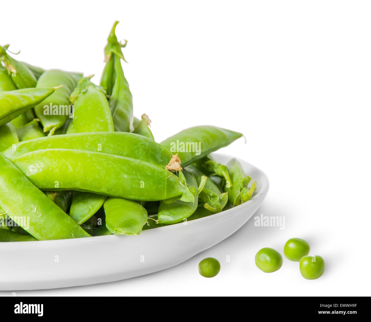 Closeup pile of green peas in pods in white plate isolated on white background Stock Photo