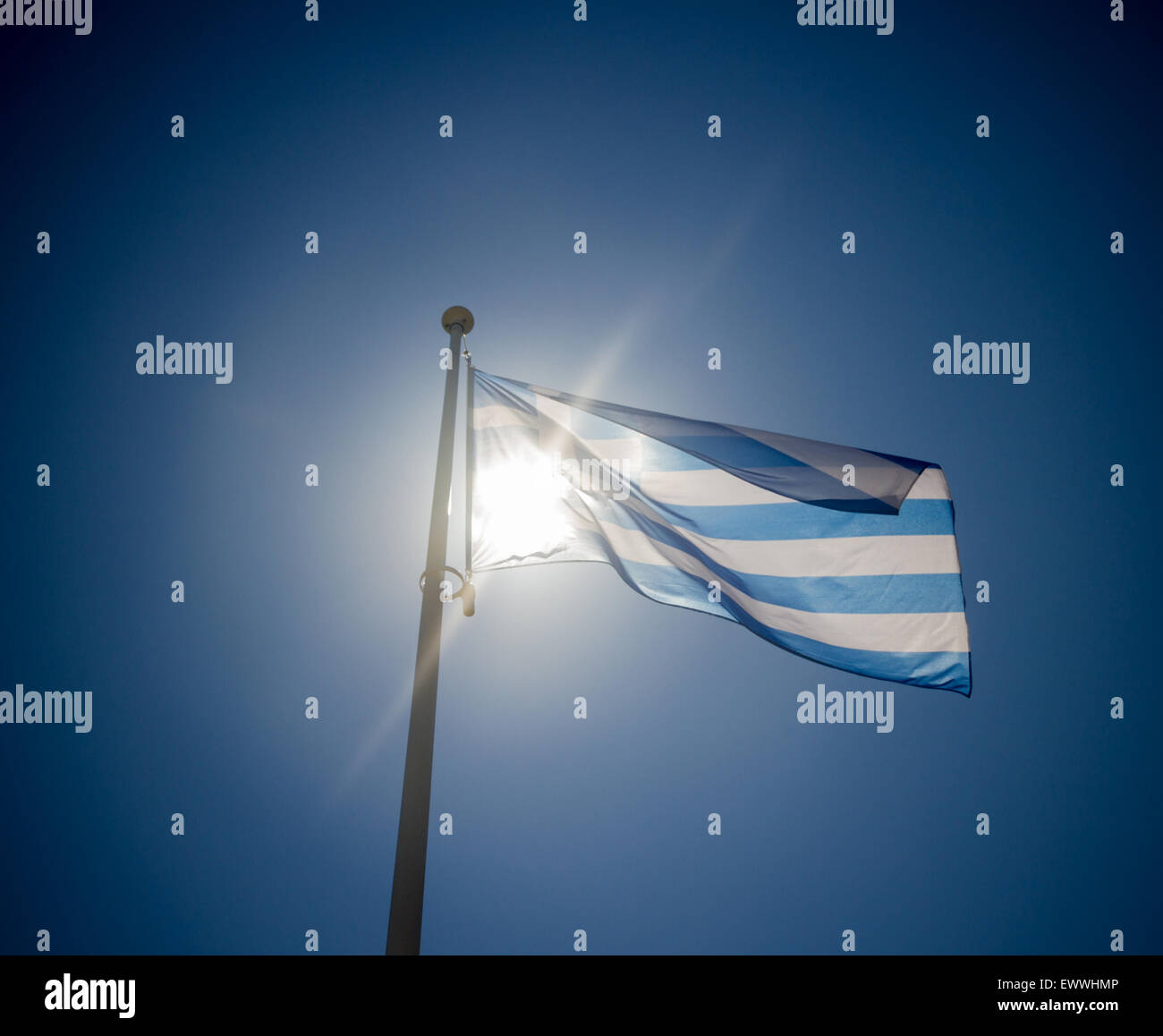 Greek flag waving before sun on blue sky, contre-jour backlighting Stock Photo