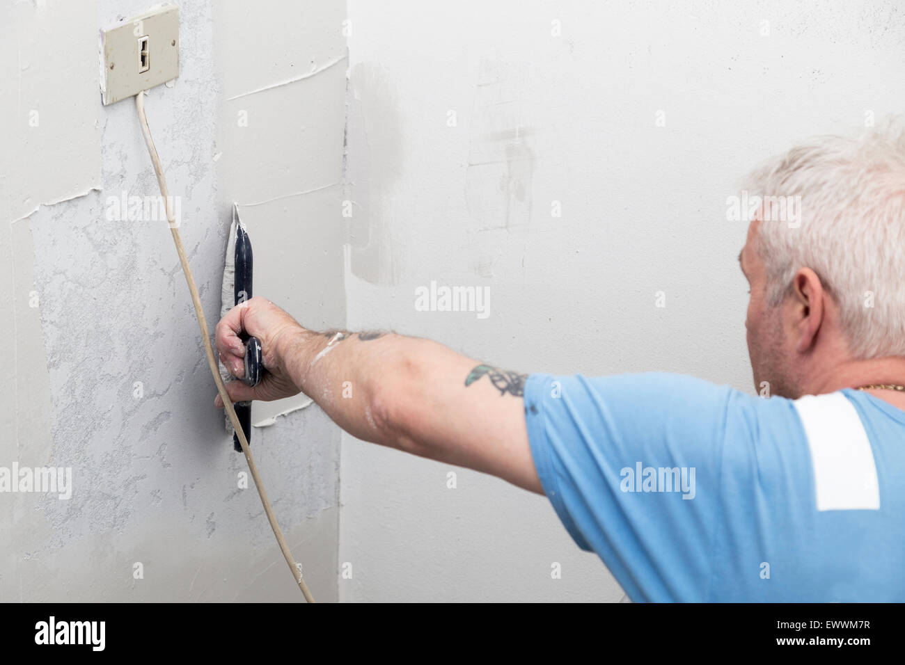 Man applying spackle to a concrete wall before painting it Stock Photo