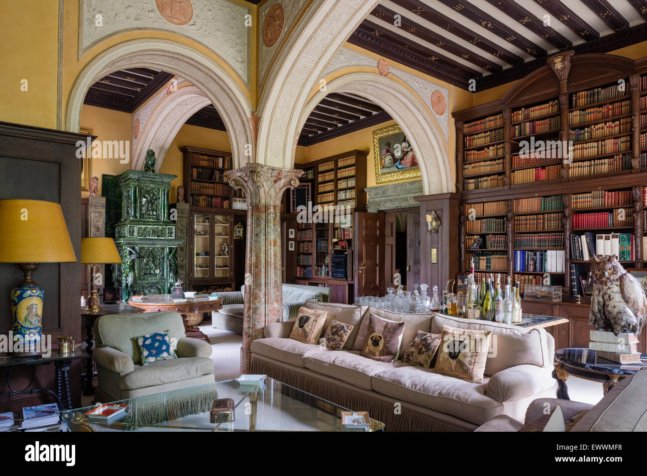 Stately drawing room with large bookcase, structural arches and green tiled stove Stock Photo