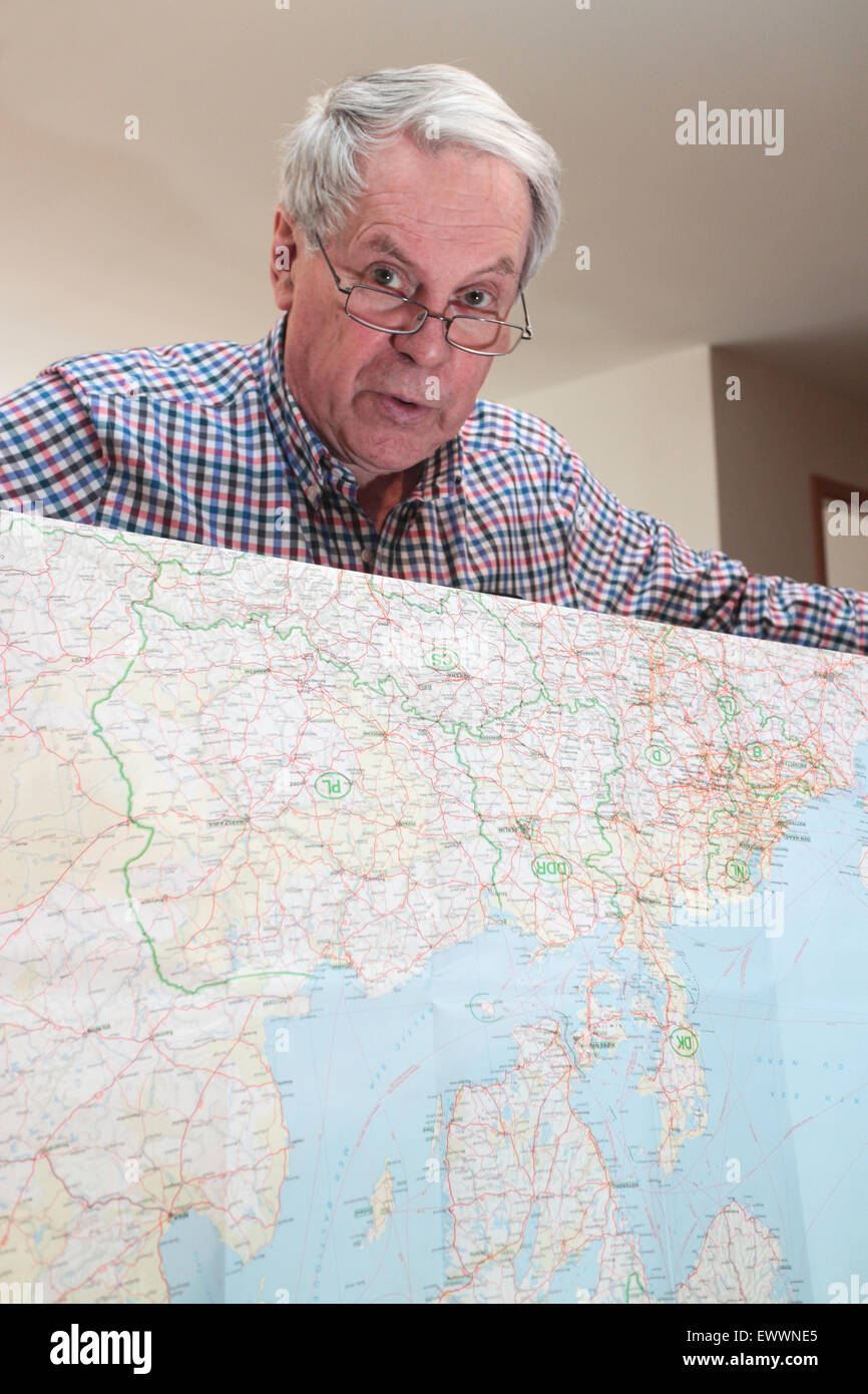 Senior citizen holding a map of europe looking at camera Stock Photo