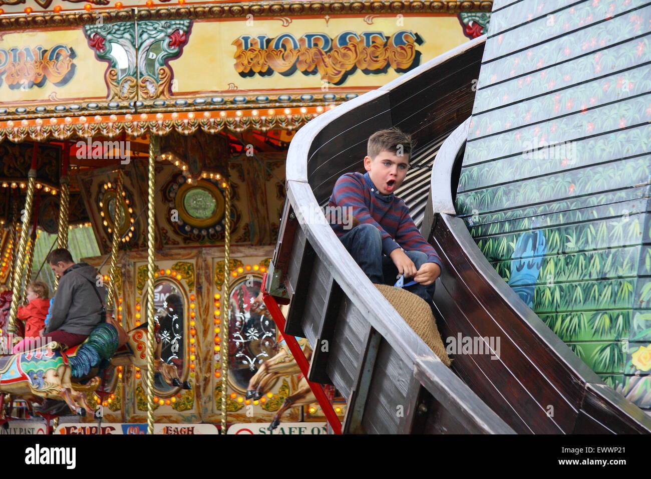 A happy childs descends a traditional helter skelter fairground ride at Chatsworth Country Fair Peak District Derbyshire England Stock Photo