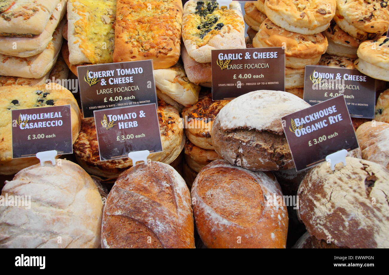 A variety of bread rolls and loaves are offered for sale at a food market in England uk Stock