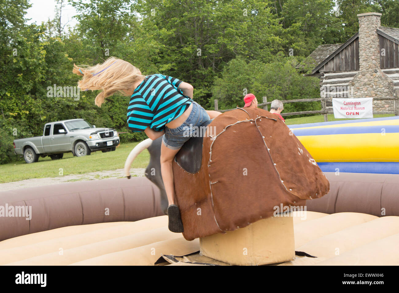 Young girl starts to come off the mechanical bull at the Canada Day celebrations at Cannington, Ontario Stock Photo