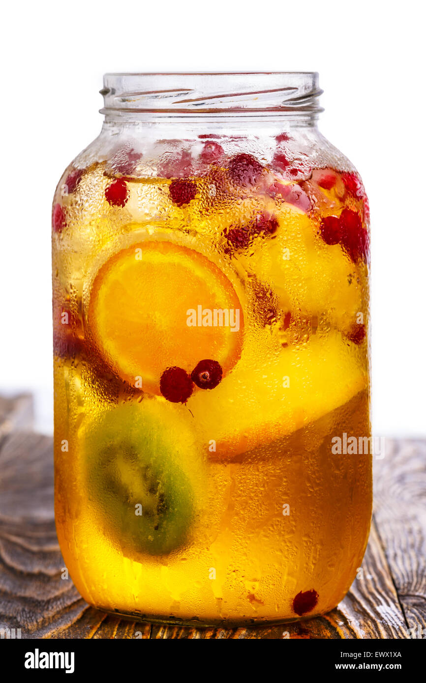 Glass jar of homemade spritzer (schorle) with carbonated apple juice served with frozen fruit wheels, ice cubes and wild cranber Stock Photo