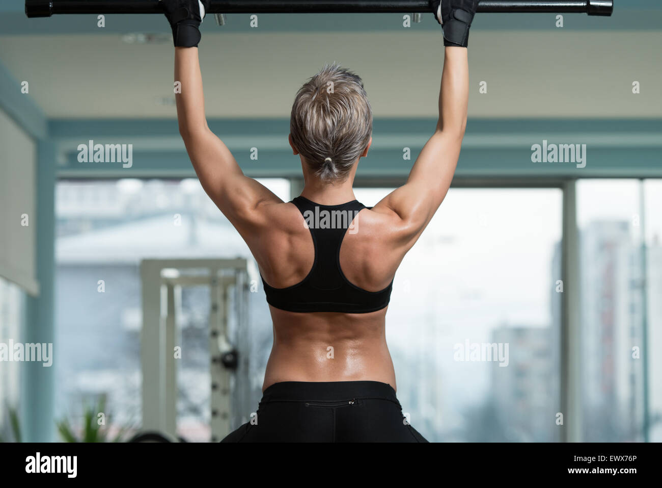 Female Athlete Doing Pull Ups - Chin-Ups In The Gym Stock Photo