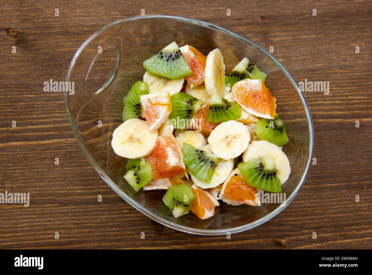 Bowl with cut fruit on wooden table top view Stock Photo