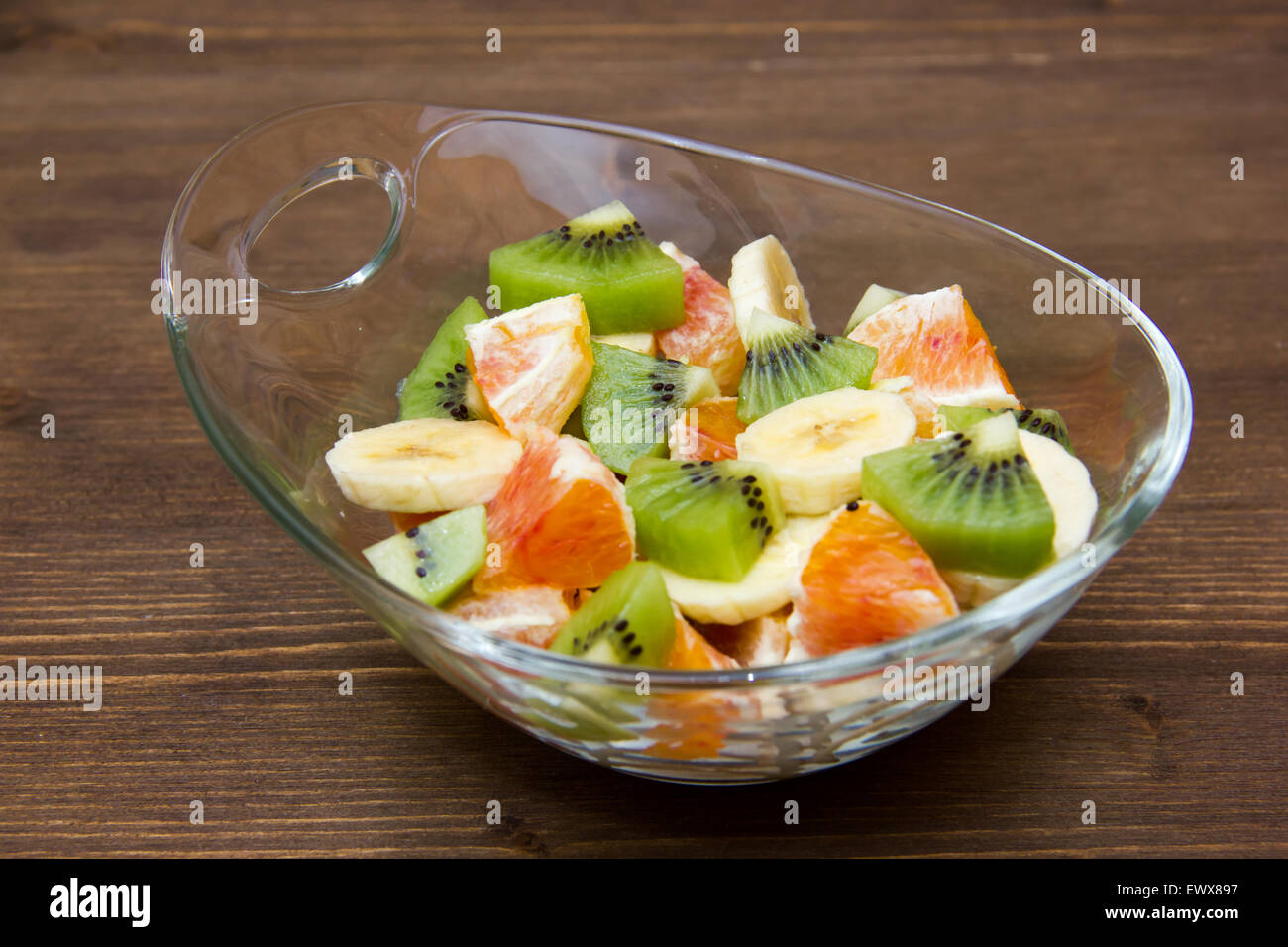 Bowl with cut fruit on wooden table Stock Photo
