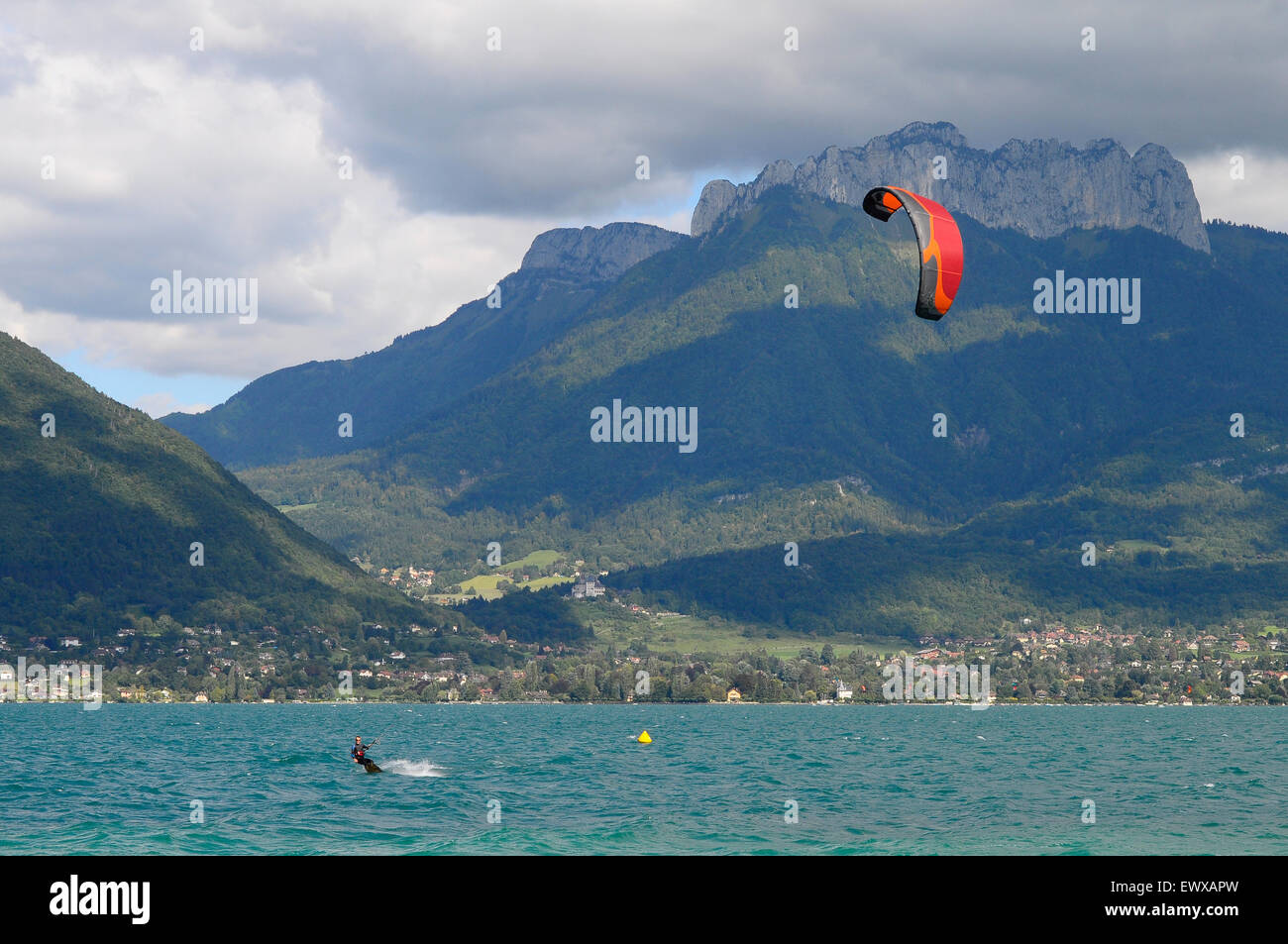 Man kitesurfing and red Kitesurf on Annecy lake in France with Forclaz mountain Stock Photo