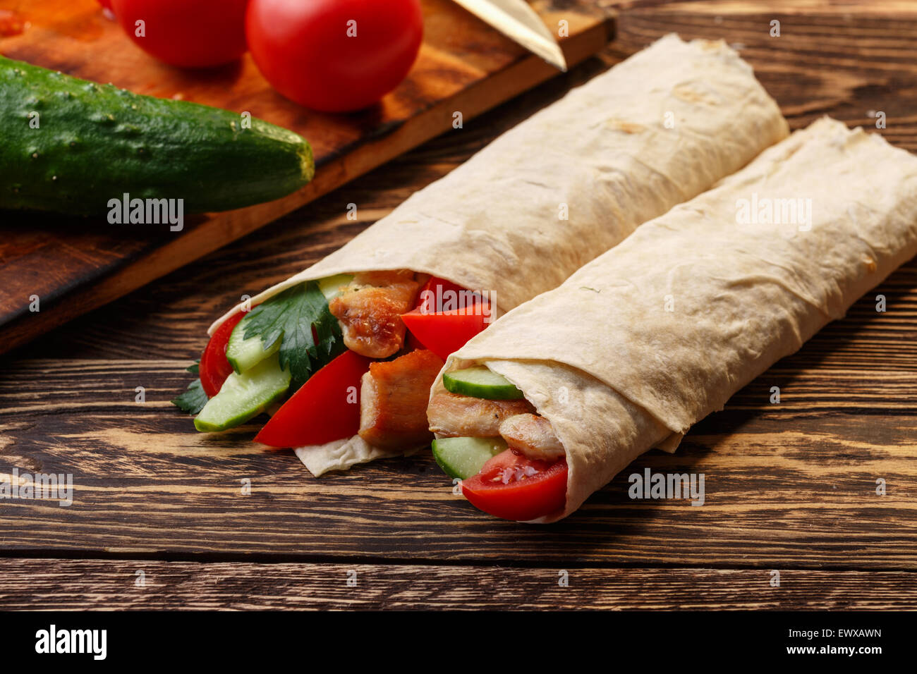 Traditional shawarma wrap with chicken and vegetables near its ingredients Stock Photo