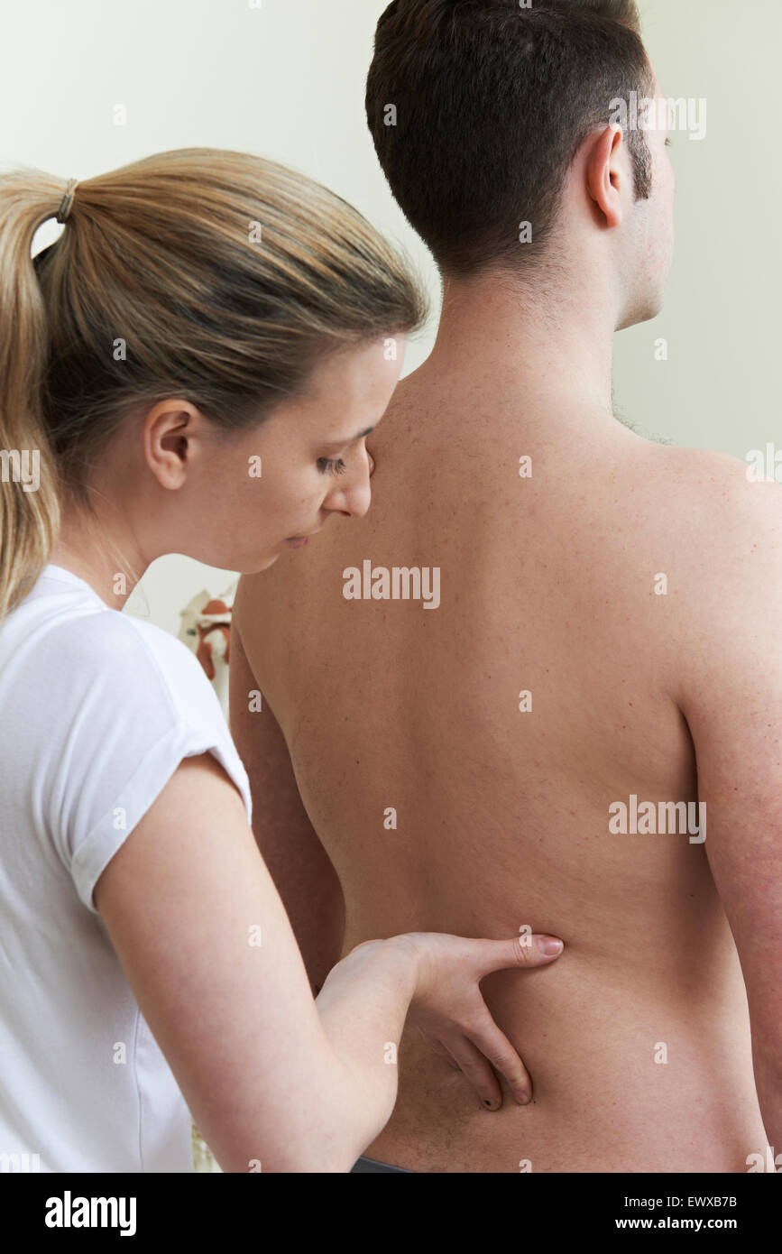 Female Osteopath Treating Male Patient With Back Problem Stock Photo