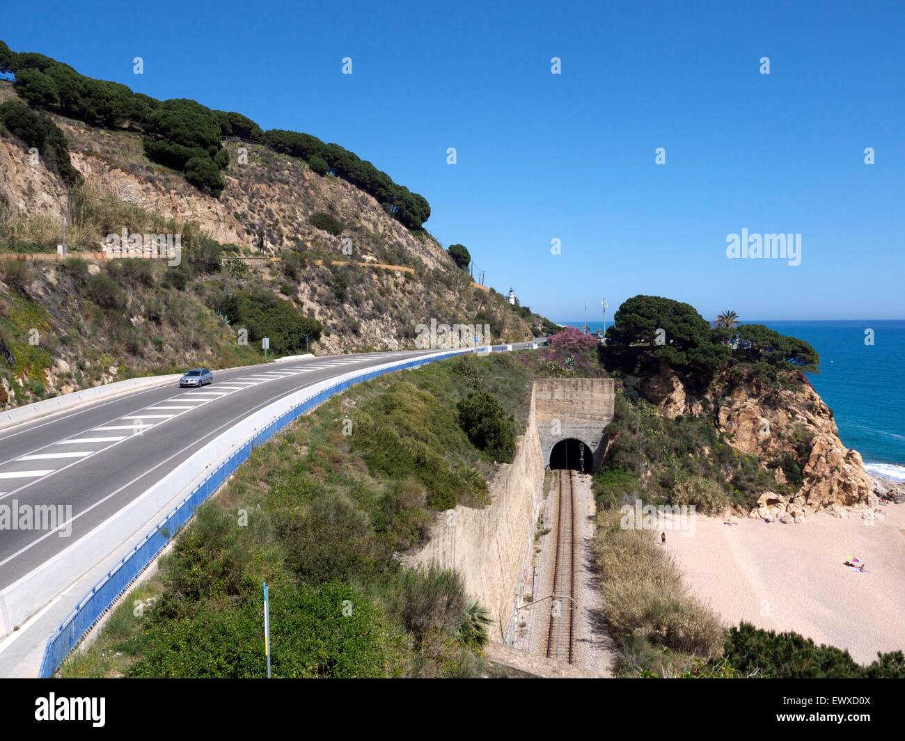 Beach with a railway running through a tunnel and a road above Stock Photo