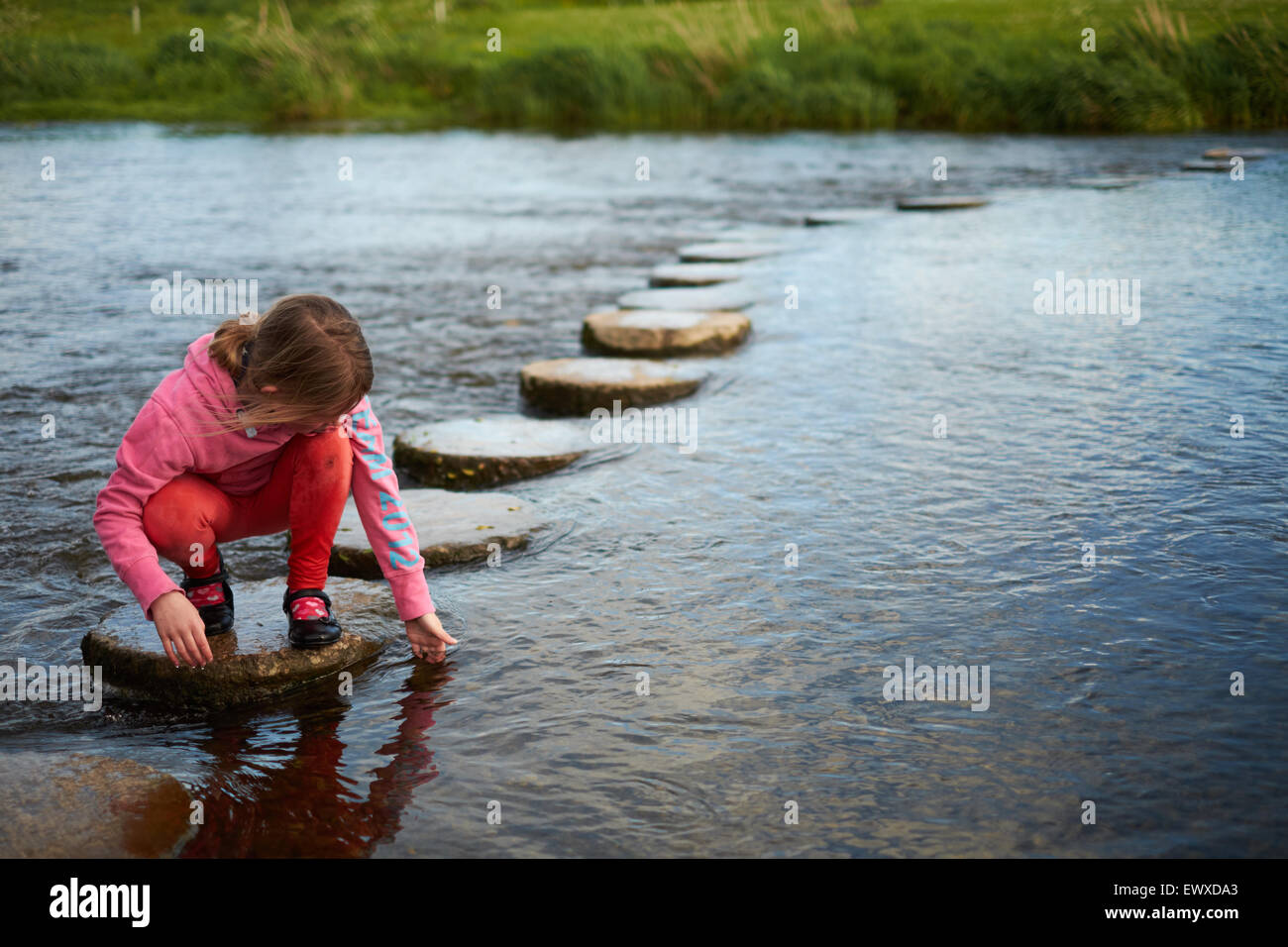 A girl plays with water on stepping stones across a river Stock Photo -  Alamy