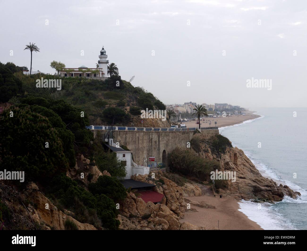 Empty beach in Spain on a gloomy looking day with a lighthouse overlooking the cliffs Stock Photo
