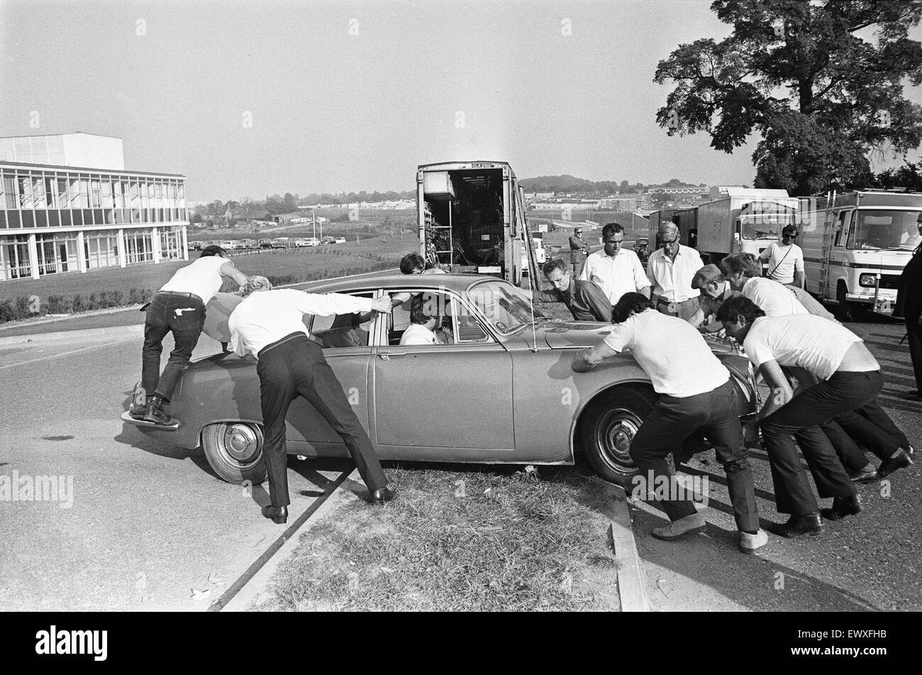 Set dressers move a Jaguar Mark II car for the next shot during